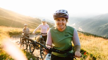 Frau lächelt auf ihren Bike | © saalbach.com, Moritz Ablinger