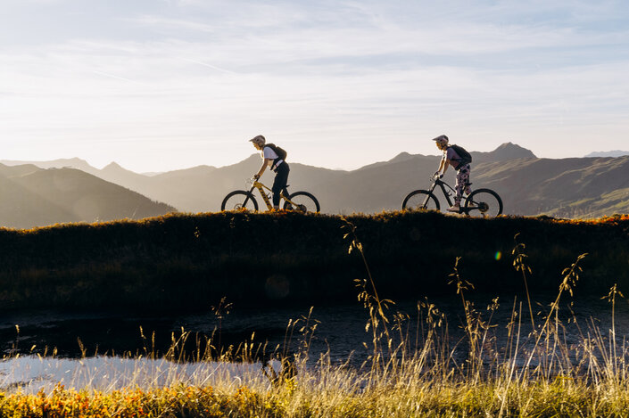 Zwei Personen am E-Mountainbike am Berg bei Sonnenuntergang | © saalbach.com, Karin Pasterer