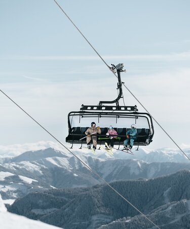 Skicircus Saalbach Hinterglemm Leogang Fieberbrunn drei Personen fahren den Skilift hinauf | © saalbach.com, Georg Lindacher