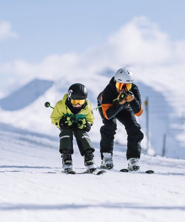 Familienurlaub in Skicircus Saalbach Hinterglemm Leogang Fieberbrunn, ein Vater und sein Sohn rasen Schuss die Piste hinunter | © saalbach.com, Mia Knoll
